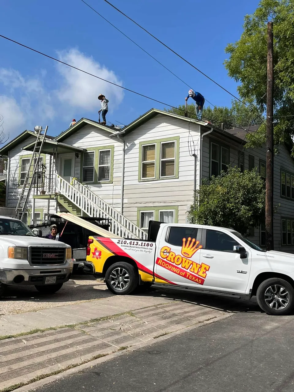 Crowne Roofing trucks parked at a roofing job site
