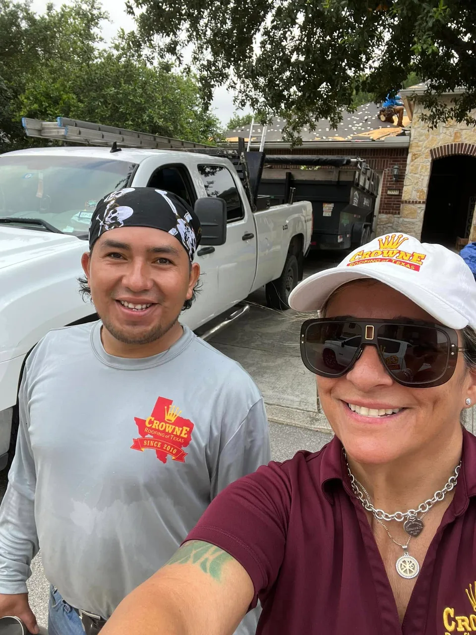 Two Crowne Roofing team members beside a work truck