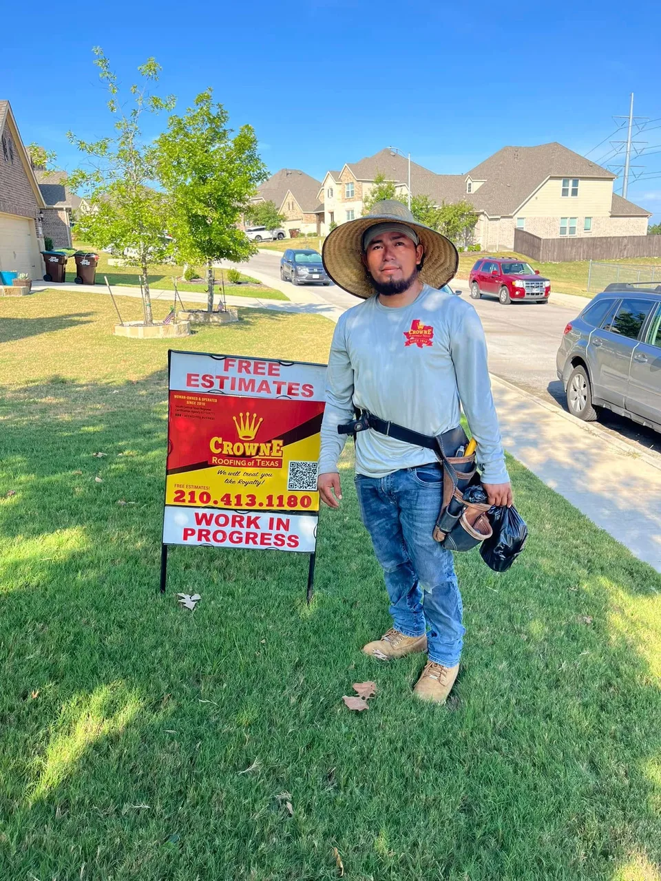 Crowne Roofing crew member standing beside a yard sign